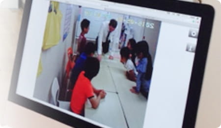 ロビーでモニターを通して見学する保護者